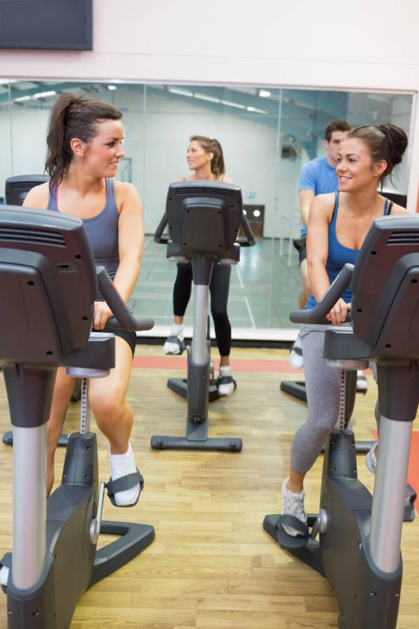 Large group of women training in gym with male trainer, in rows