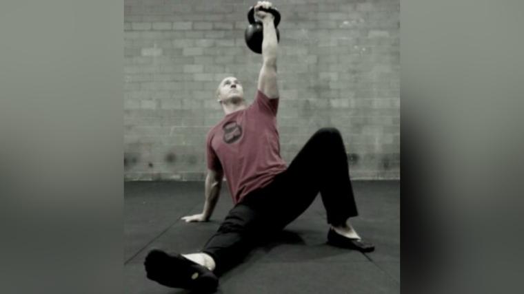 A man holds a kettlebell at a Turkish Get-Up site