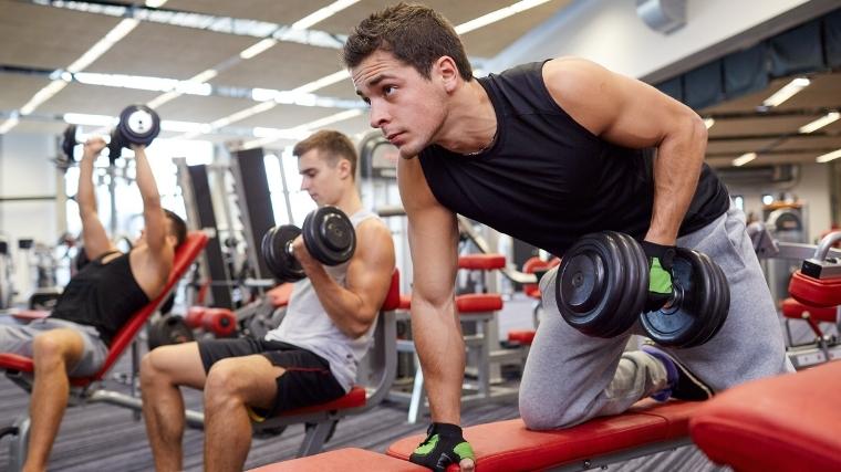 A group of runners carry heavy weights together at a gymnasium