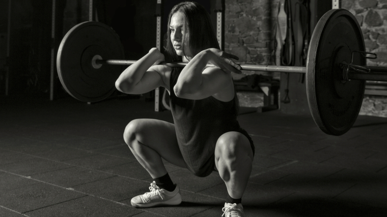 black and white photo of women holding barbell in a deep squat position