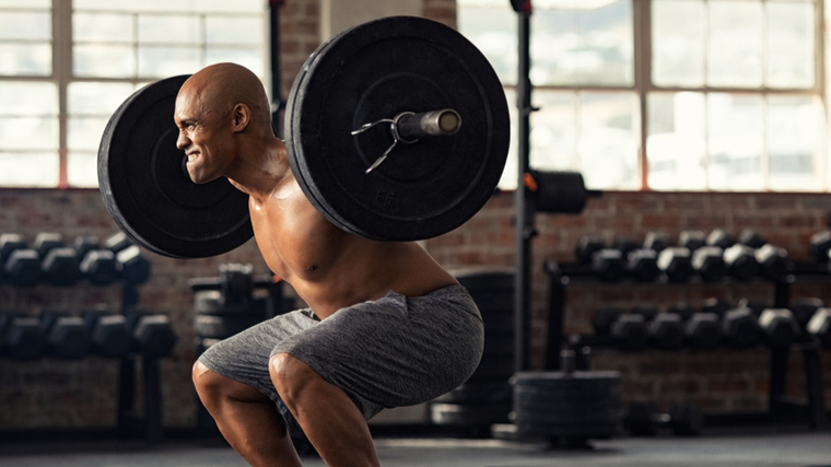 bald man exercising intensely performing barbell squats