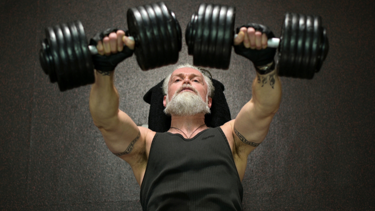 grey-haired man performing dumbbell chest press exercise