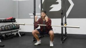 Man holding barbell in arms while squatting