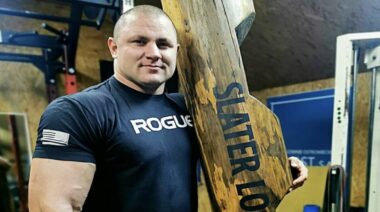 Polish Strongman Mateusz Kieliszkowski smiling while holding a strongman log for the log press