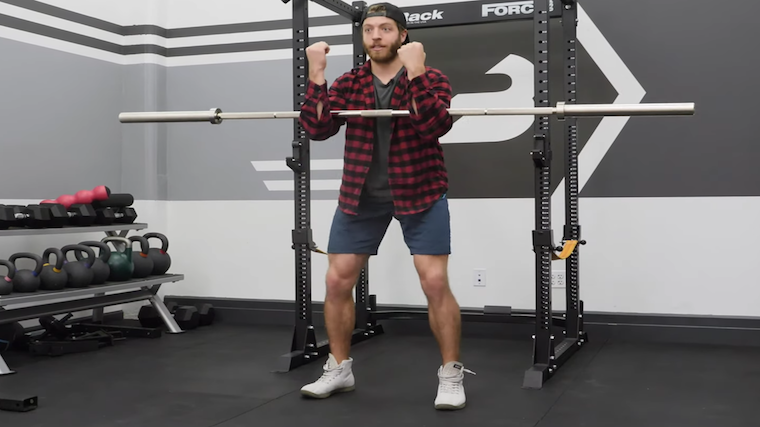 Man in gym standing while holding barbell in arms