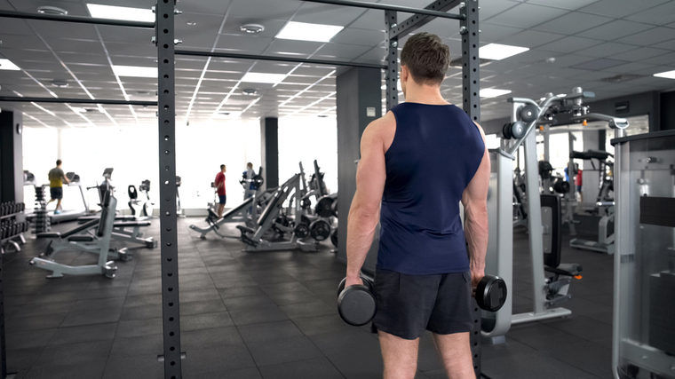 Muscular man in gym holding dumbbells