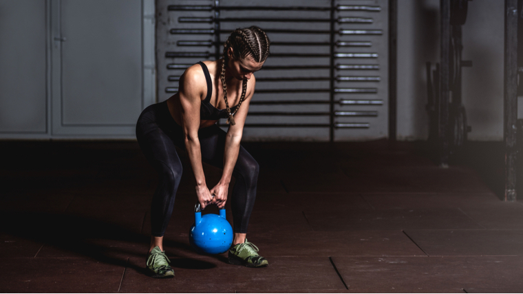 Muscular woman in gym performing kettlebell exercise