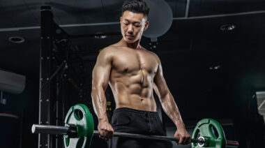 Muscular asian man lifting barbell