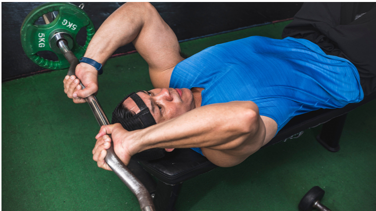 Man in gym performing lying triceps exercise