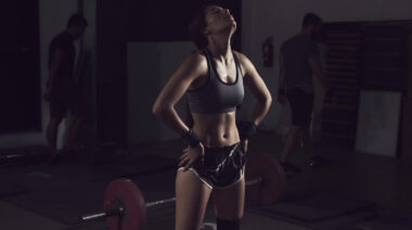 Woman in dark gym tired after workout