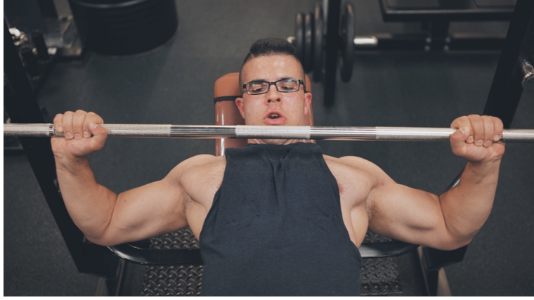 Muscular man with glasses lifting weights
