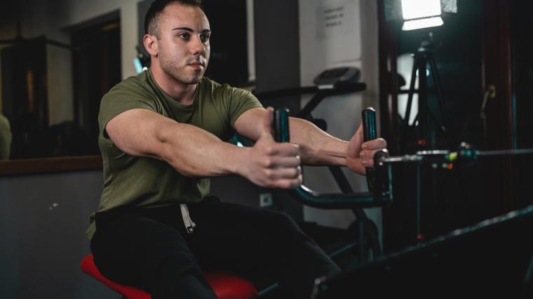 Young man in gym performing seated cable row