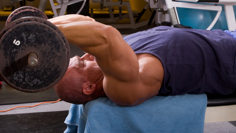Muscular man in gym flexing muscles during triceps exercise