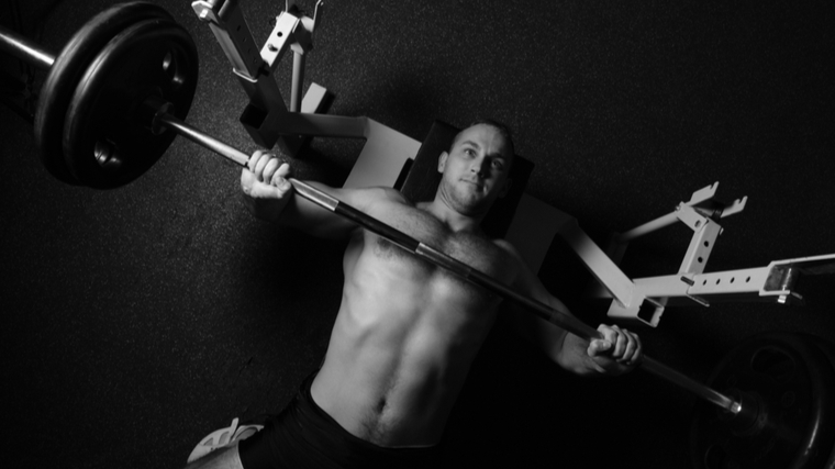 Black and white photo looking down at man performing bench press