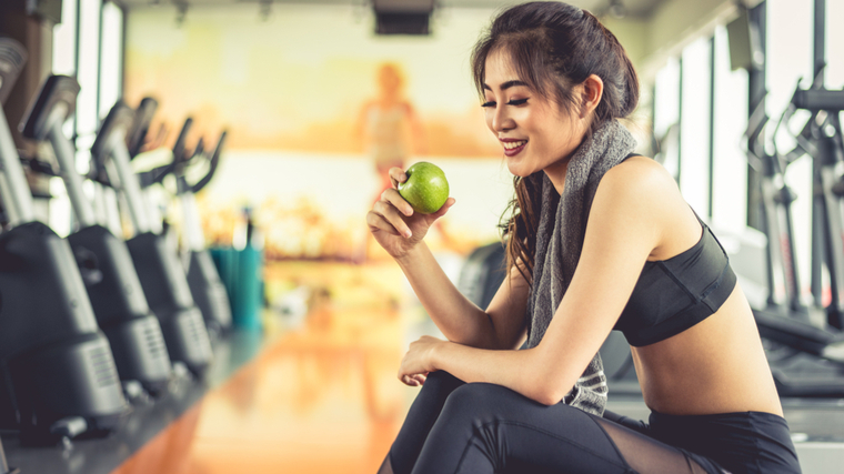 Woman in gym eating apple