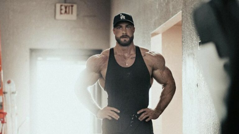 Chris Bumstead poses in a hallway with a cinematic-like shot in Spring 2022
