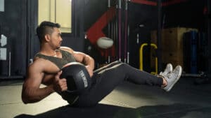 Man on ground performing ab exercise with medicine ball