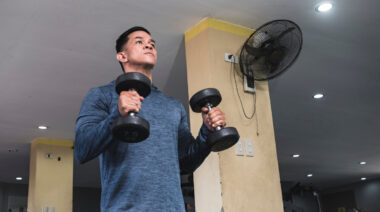 Man in gym performing curl with two dumbbells