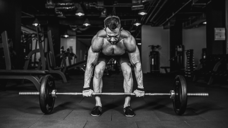 black and white phot of bodybuilder preparing to lift a barbell from the ground