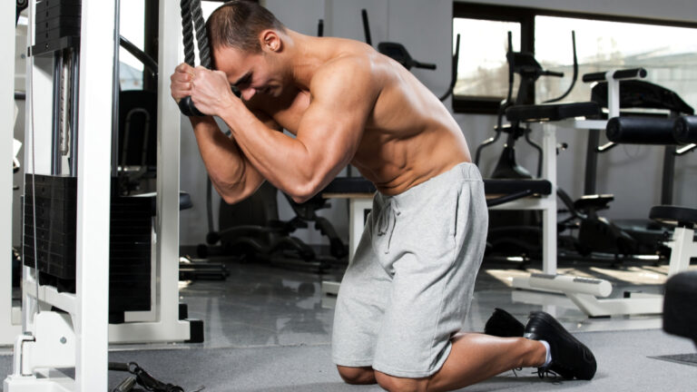 Muscular man kneeling in gym performing ab exercise