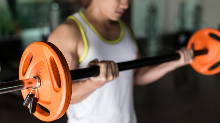 out of focus person performing barbell curl with weights in focus