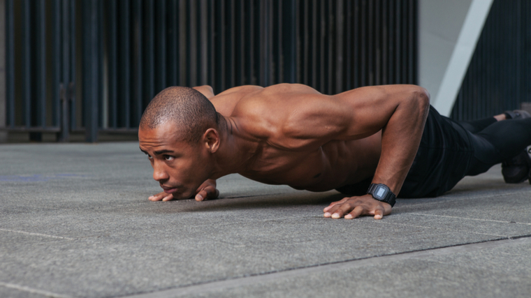 shirtless person performing push-ups outdoors