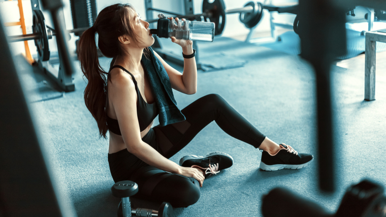 person sitting in gym drinking water