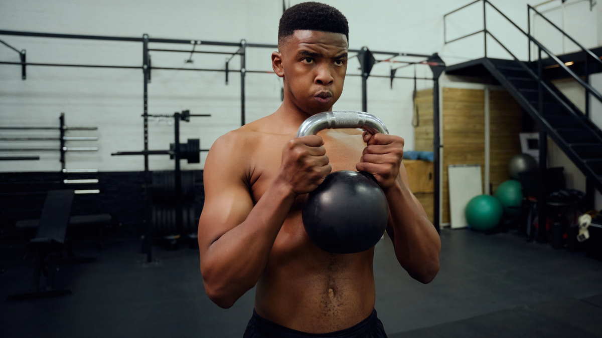 Concentrated man doing dumbbell workout. Well trained body with bulky  muscles. Sport equipment and weightlifting. Stock Photo