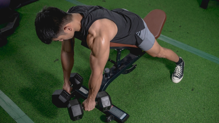 Man in gym performing two-dumbbell row on bench
