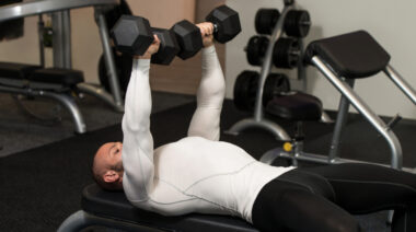 man in gym performing flat bench dumbbell chest press