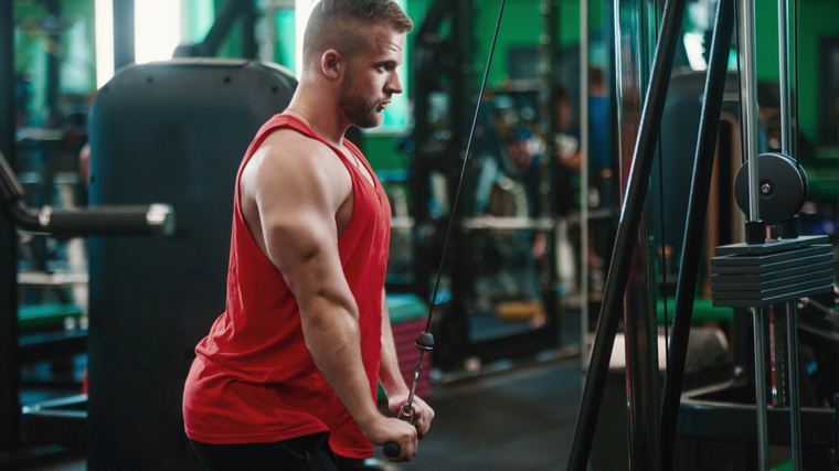 person wearing red tank top performing cable triceps exercise