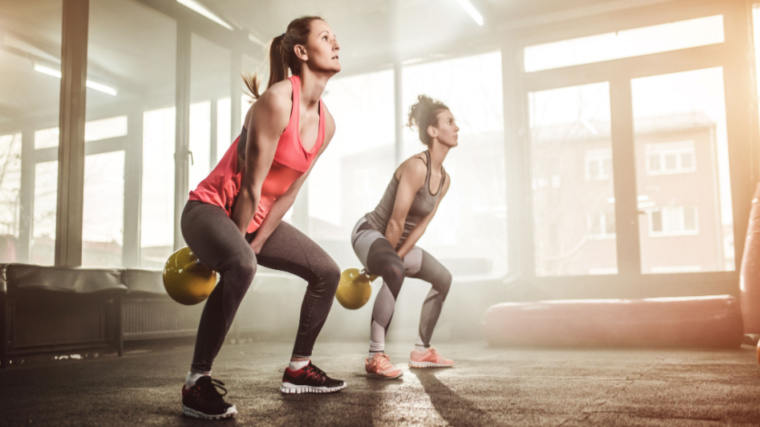 two people performing kettlebell squats