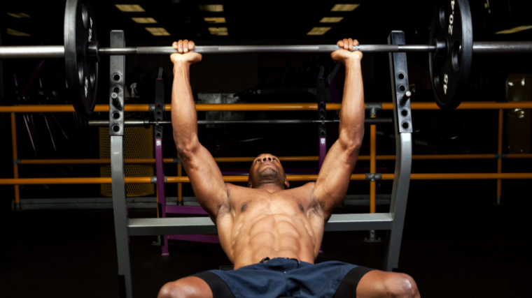 muscular person in gym performing barbell press