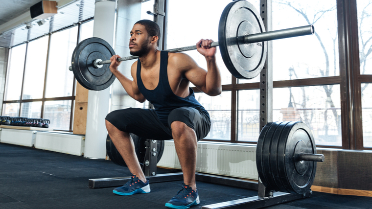 person in gym doing barbell squat