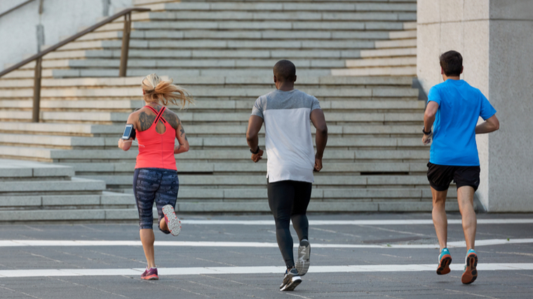 Three people running outdoors towards the stairs