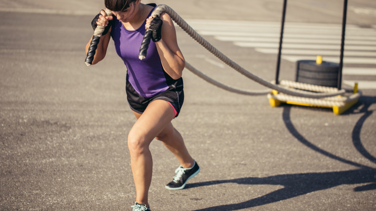 person outdoors pulling weighted sled with rope