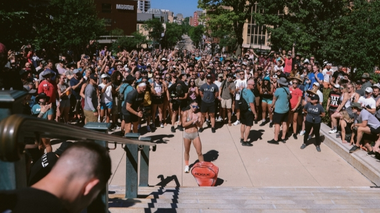 Woman in shorts and sports bra stands in front of a sandbag at the foot of the stairs of the Wisconsin Capitol building.