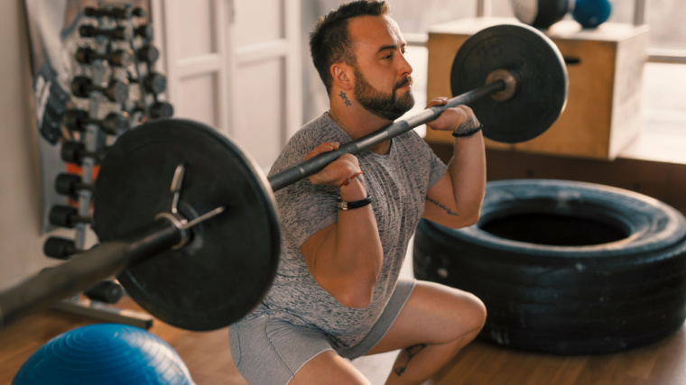 tattooed person performing front squat