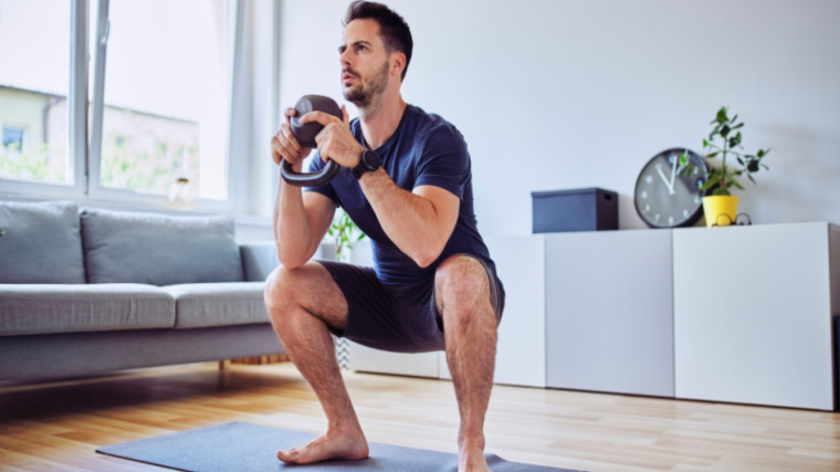 person at home doing squat with kettlebell