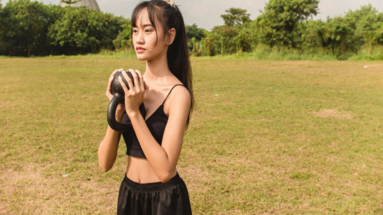 person outdoors holding kettlebell
