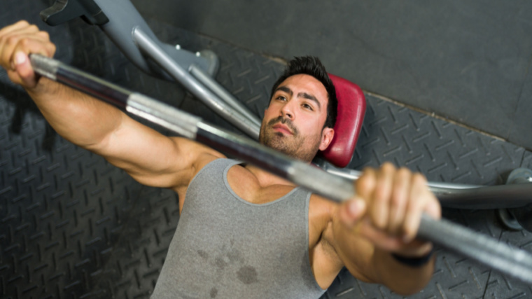 person in gym performing bench press