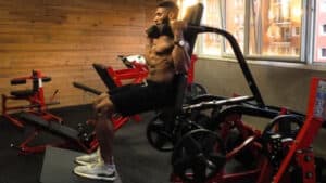 Shirtless muscular person on squat machine