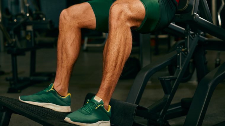 legs of person in gym squatting on machine 