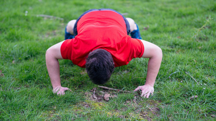 person doing push-ups on grass