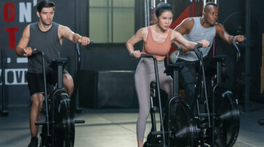 three people in gym on air bikes