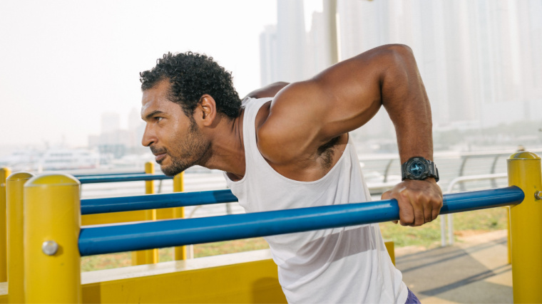 muscular person performing chest dip outdoors