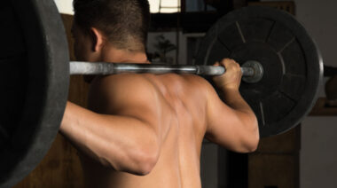 shirtless person holding barbell
