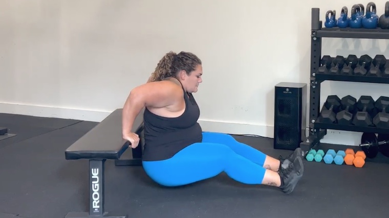 person in gym doing dips on bench