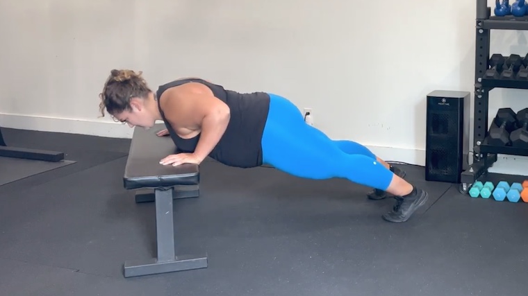 person doing push-up in gym with hands on bench