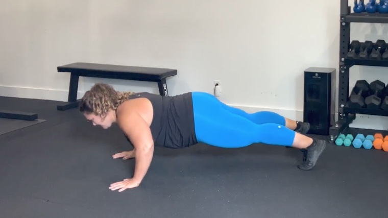 person in gym doing push-up on floor